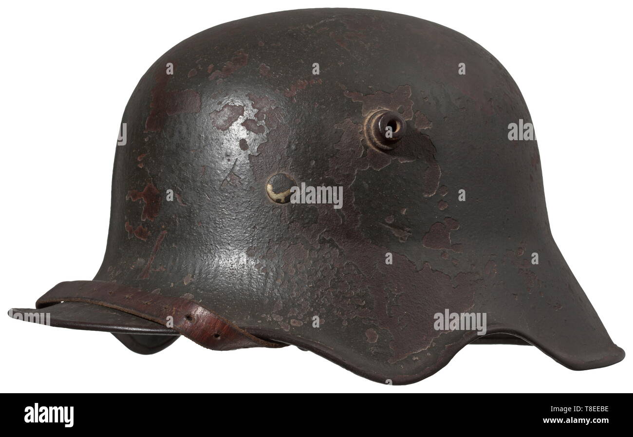 A steel helmet M 18 with ear cut-outs The dark green veneer with large blemished areas beneath which the original field-grey paint is clearly visible. The interior stampings are no longer decipherable due to the paint application, with only '..R 1..' readable at the crown. Complete with M 1931 interior fittings and corresponding chin strap. historic, historical, army, armies, armed forces, military, militaria, 20th century, Editorial-Use-Only Stock Photo