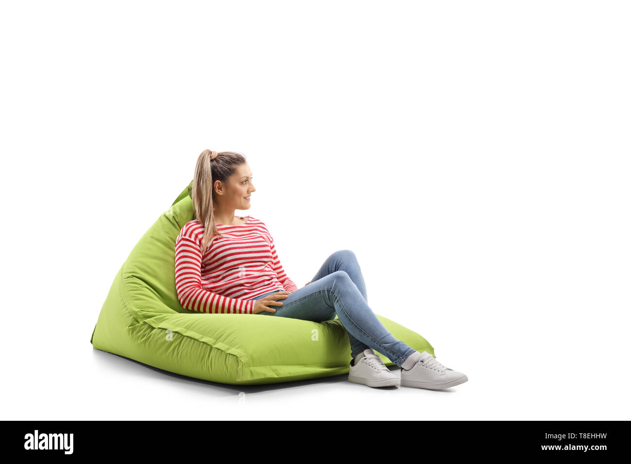 Full length profile shot of a young casual woman sitting on a bean bag ...