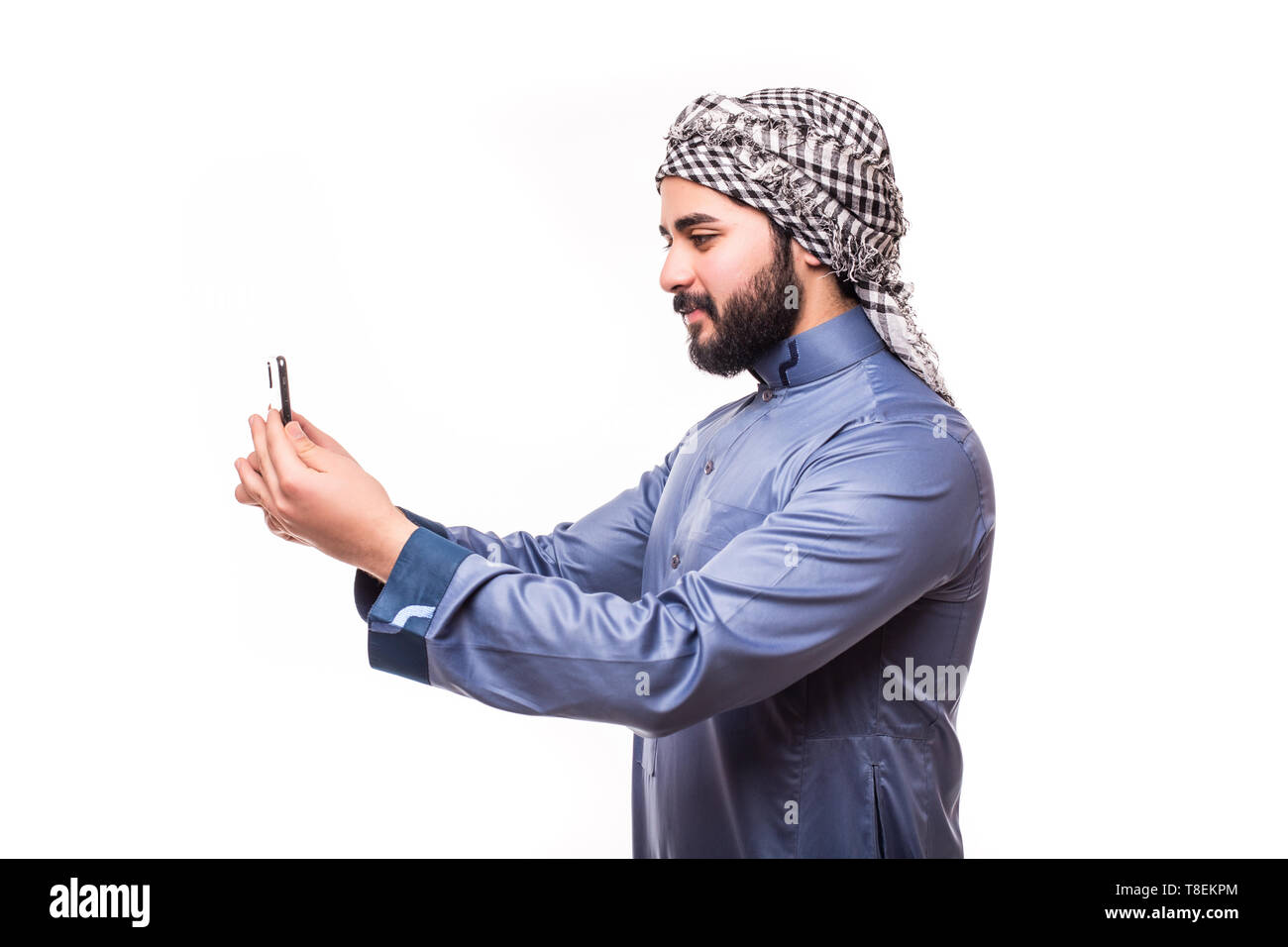 Young arab man wearing in traditional abaya clothes with phone on white background Stock Photo