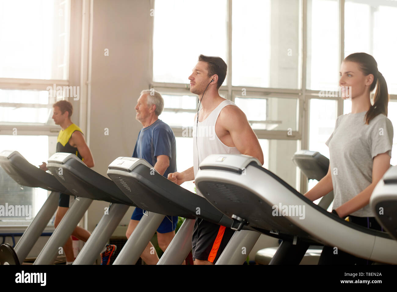 Group of people on treadmill at gym. Handsome young man running on
