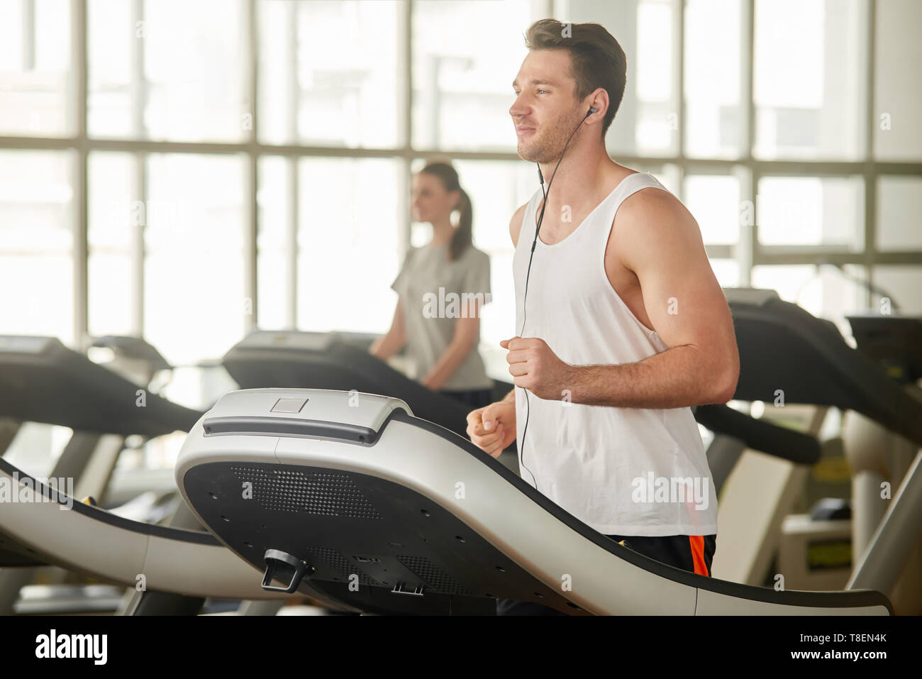 Young athletic man running on treadmill. Handsome muscular guy working