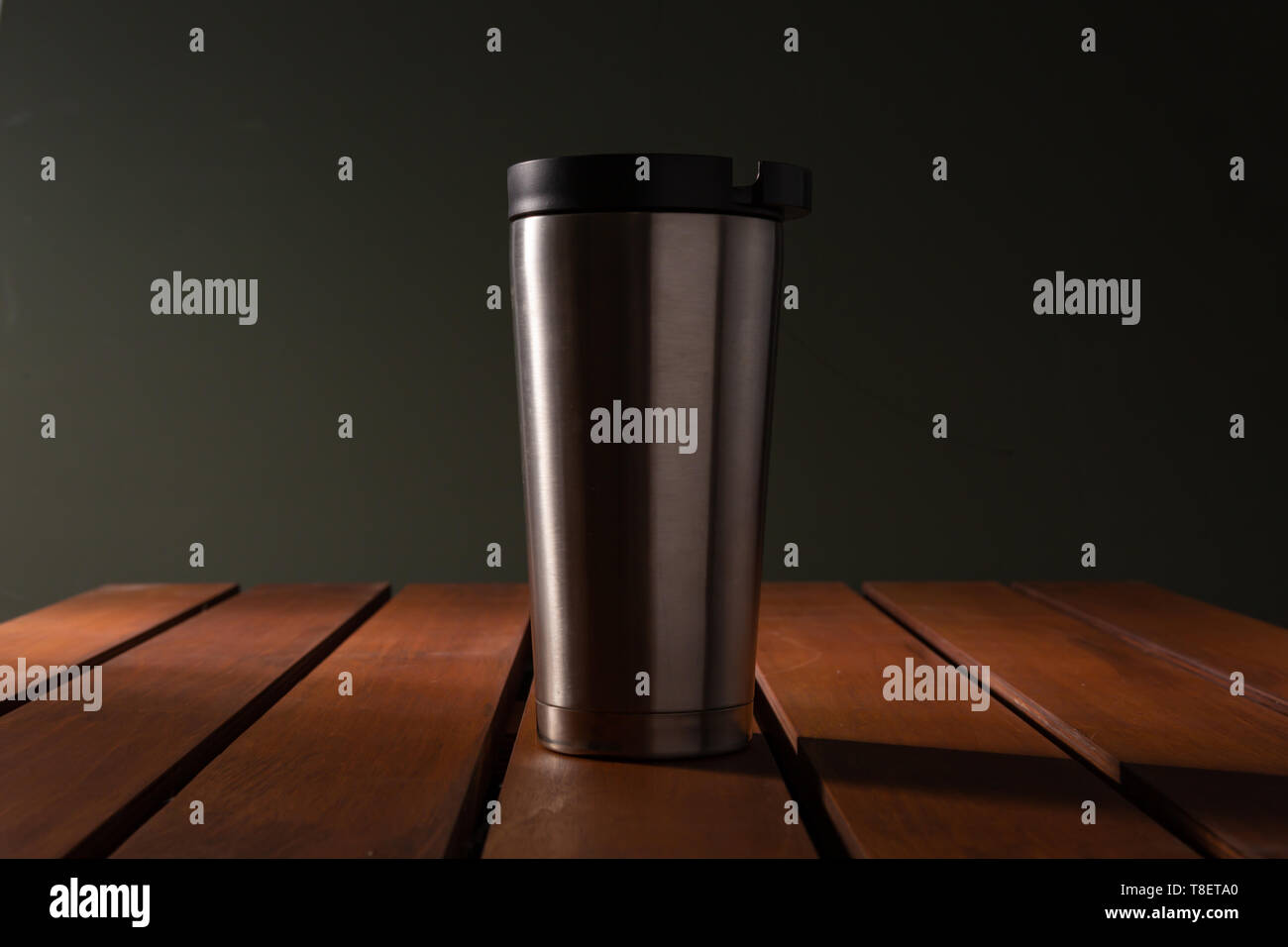 Stainless tumbler on wooden tables in dark lighting Stock Photo - Alamy