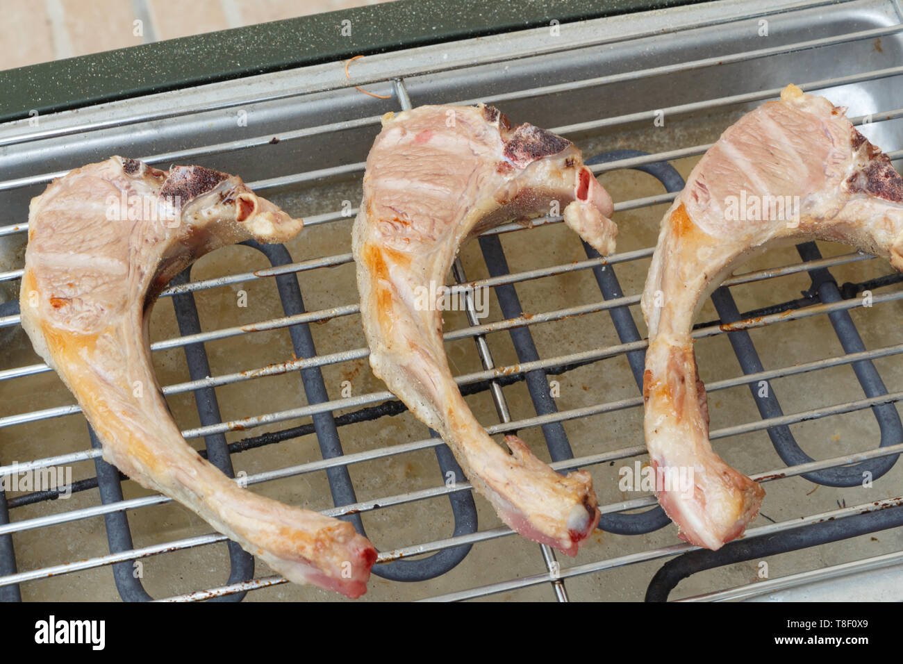 Lamb chops on the grid of an electric barbecue during summer Stock Photo