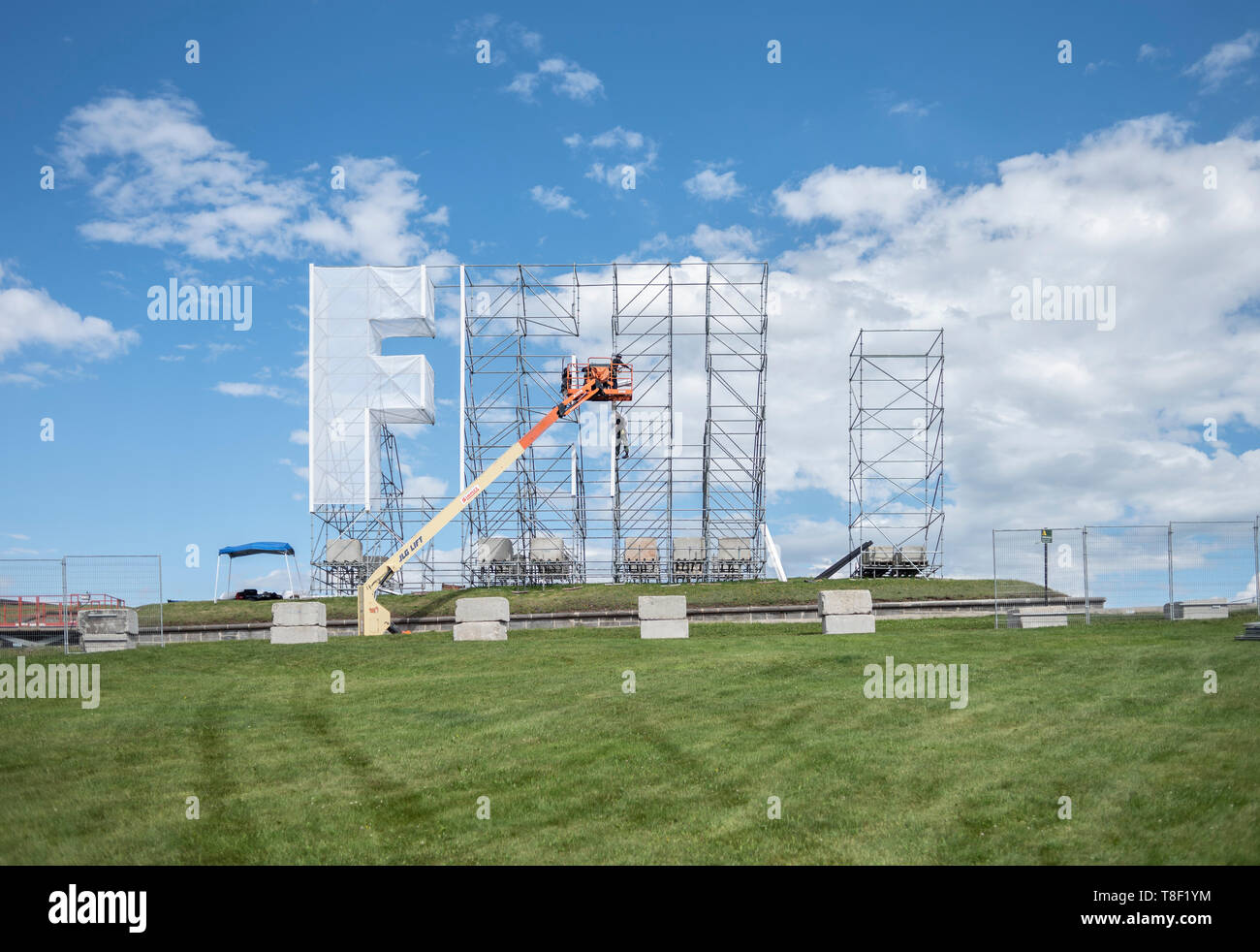Construction workers installing large sign in an empty field. Stock Photo