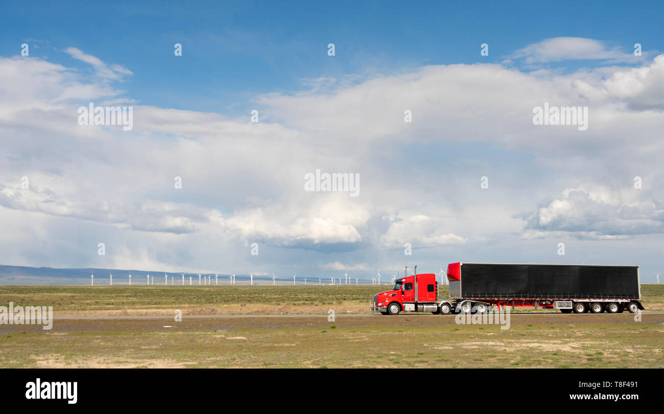 Red big rig semi truck with black cargo trailer on a Utah Highway Stock Photo