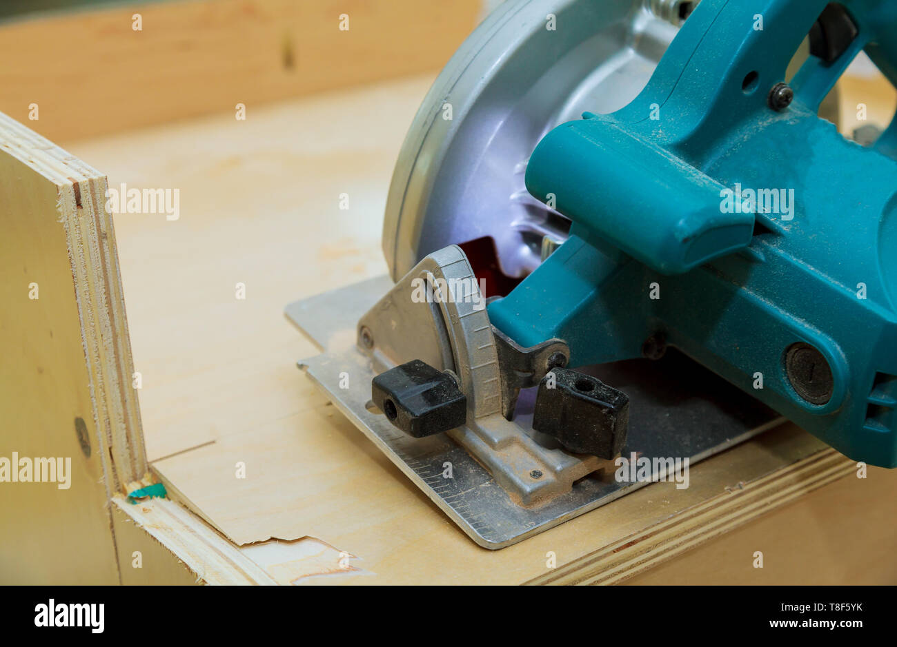 Carpenter using circular electro saw cutting kitchen furniture Stock