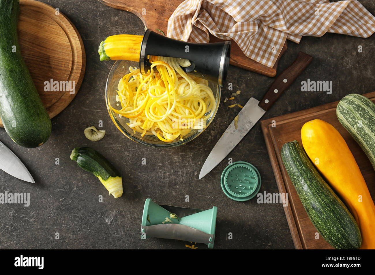 Fresh zucchini spaghetti with spiral grater and vegetables on dark table Stock Photo