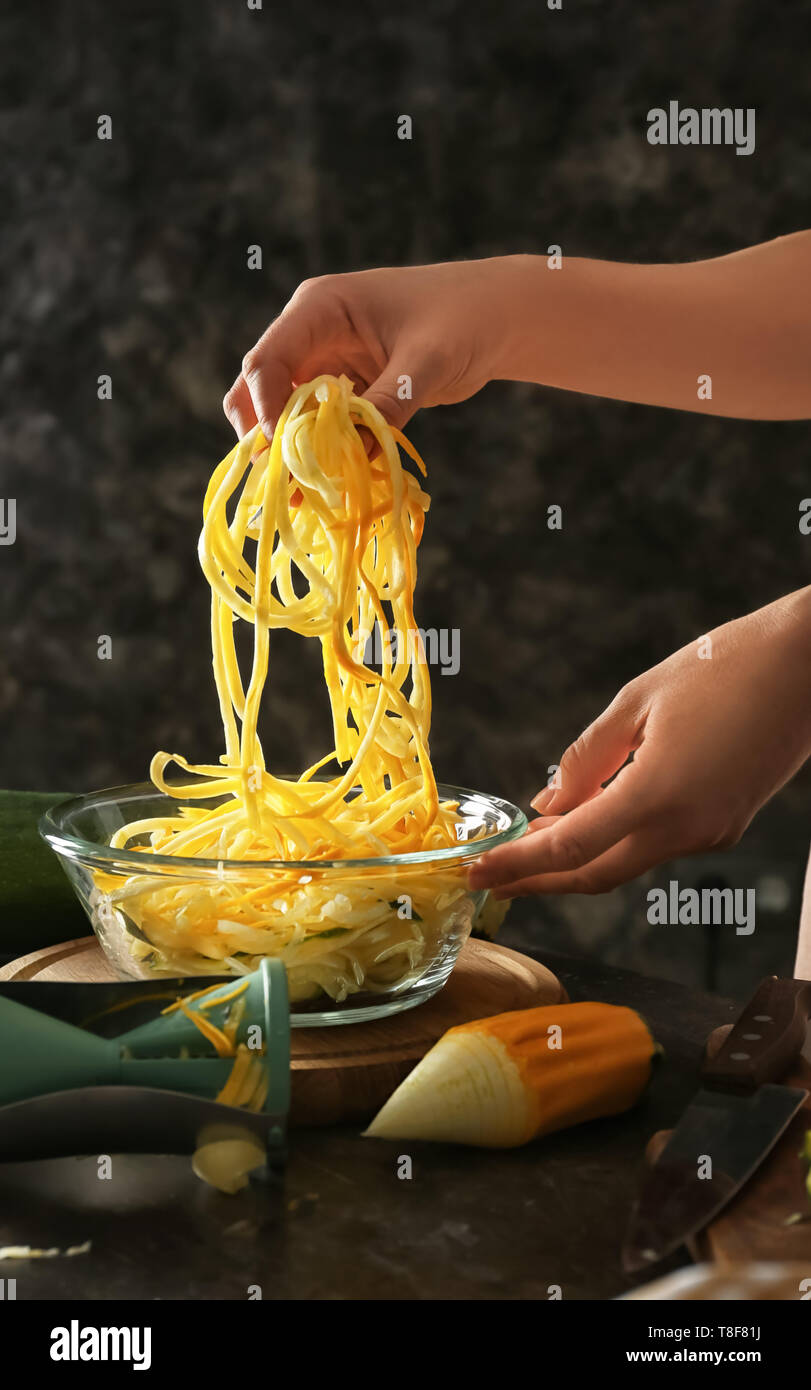 Woman holding fresh zucchini spaghetti over bowl Stock Photo