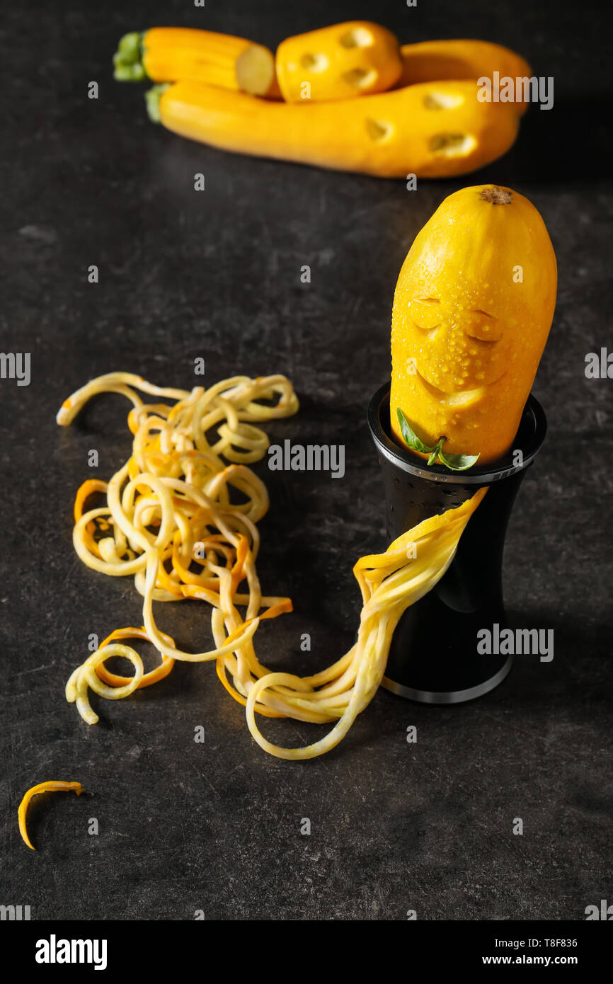 Creative composition with spiral grater and zucchini spaghetti on grey background Stock Photo