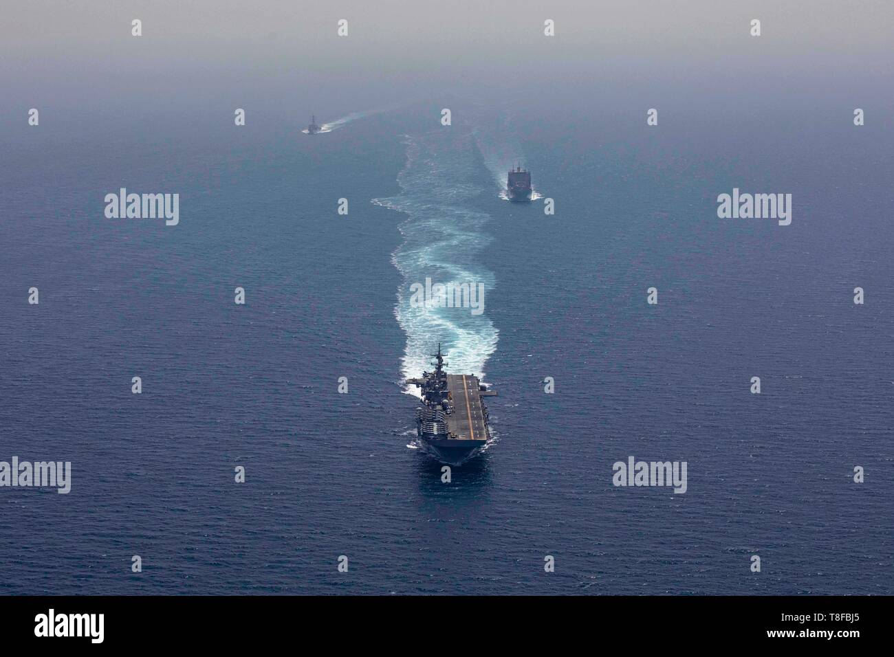 The U.S. Navy Wasp-class amphibious assault ship USS Kearsarge, center, the dry cargo and ammunition ship USNS Alan Shepard, right, and the Arleigh Burke-class guided-missile destroyer USS McFaul transit the Strait of Hormuz May 7, 2019 in the Arabian Sea. The patrol is part of additional forces being sent to the Middle East to counter what the Trump administration calls clear indications of threats from Iran. Stock Photo