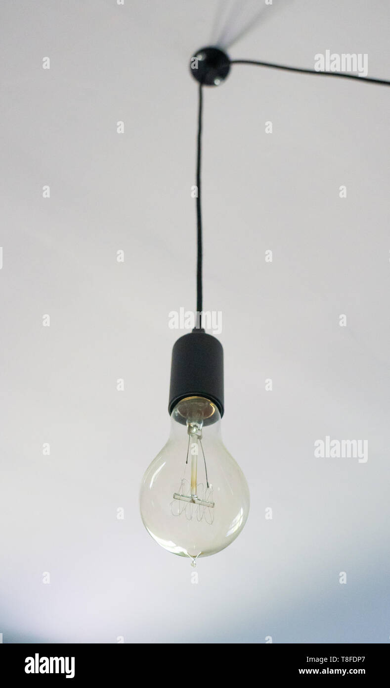 one vintage light bulb hangs in a dining room Stock Photo - Alamy