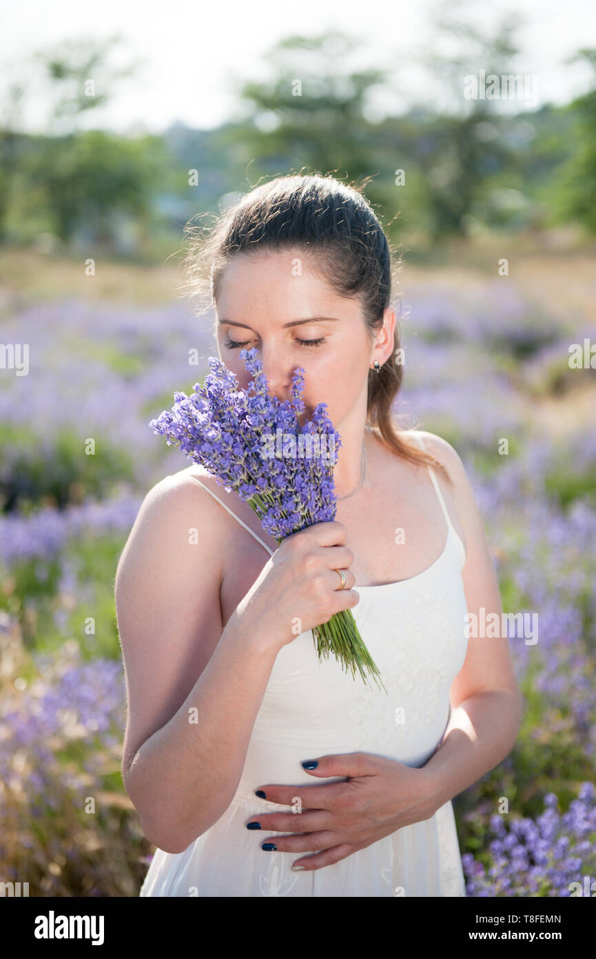 young beautiful woman in white dress holding bouquet of lavender flower sniffing outdoors leisure lifestyle Stock Photo