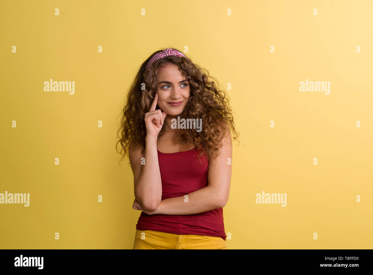 Portrait of a young woman with headband in a studio on a yellow background. Stock Photo