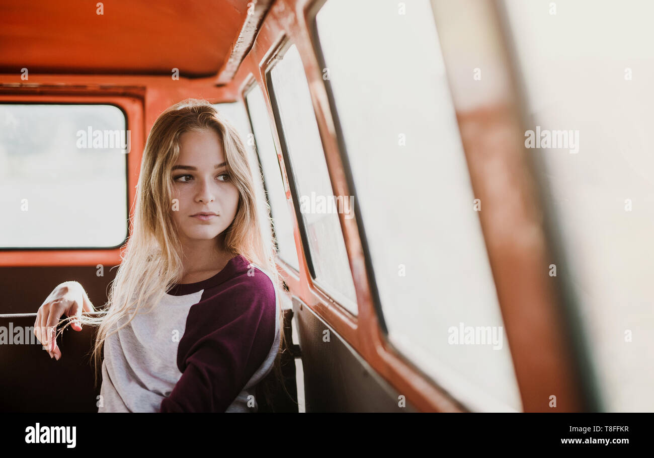 A young girl sitting in a car on a roadtrip through countryside. Stock Photo