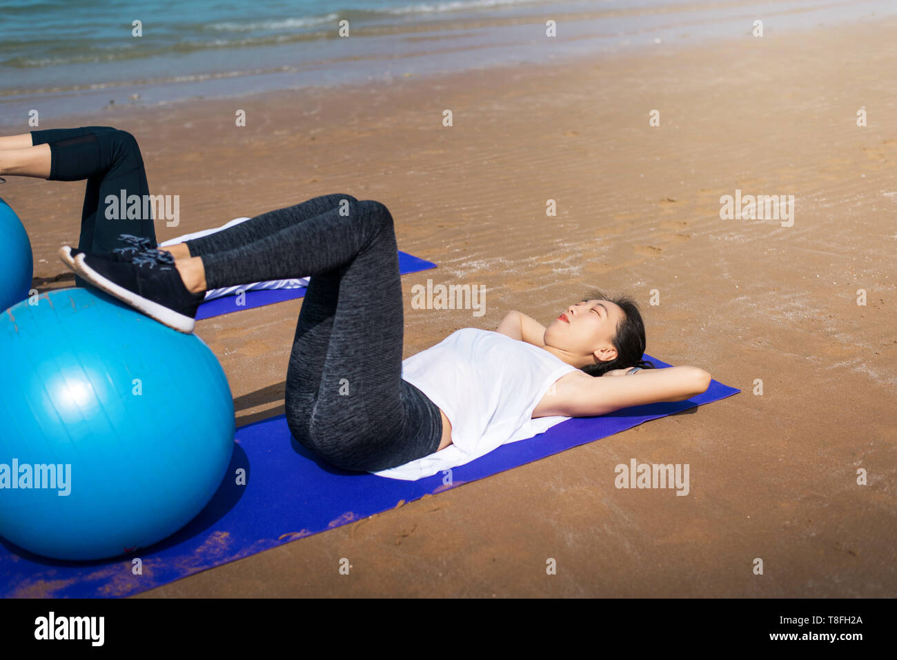 Woman exercising with pilates yoga ball on the beach Stock Photo
