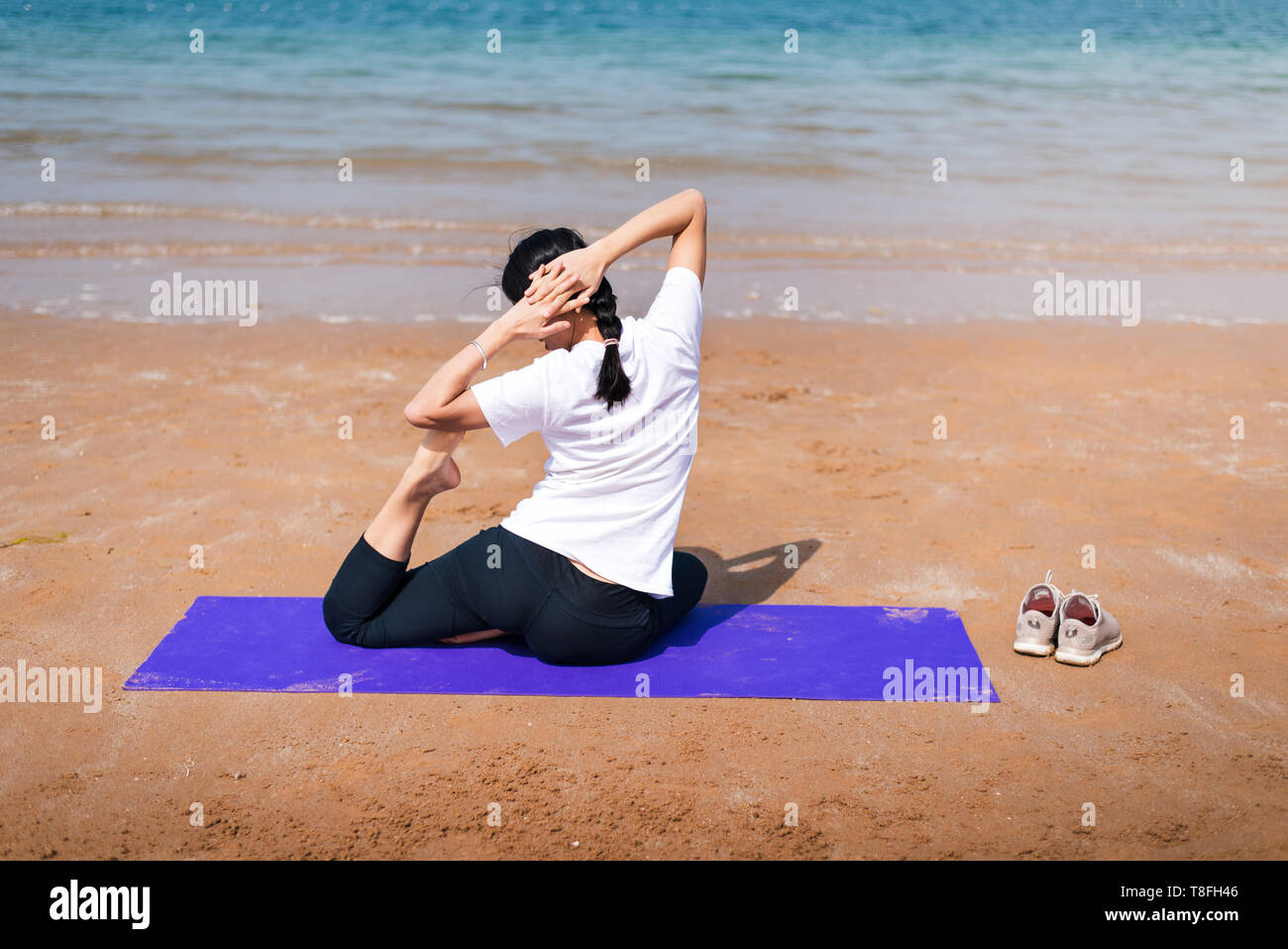 Female friends practicing yoga on the beach back view Stock Photo