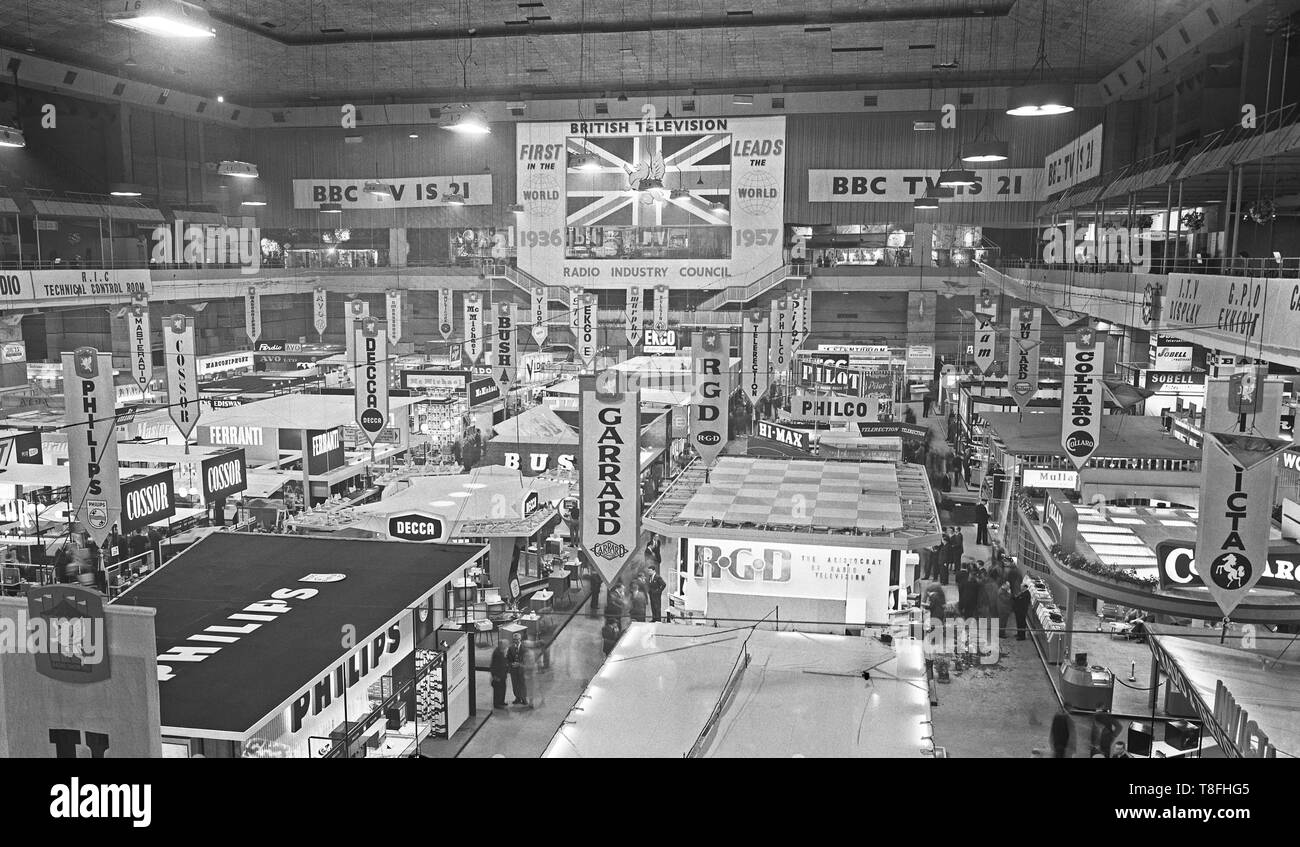 The Radio Exhibition at London's Earls Court in 1957. A banner at the far end of the room states that 'British Television leads the World' and that TV broadcasts began in 1936 with the BBC being the first in the world with 1957 its 21st birthday. On the floor of the hall are trade display stands for electronics companies such as Decca, Philips, Garrard, Philco and Bush Stock Photo