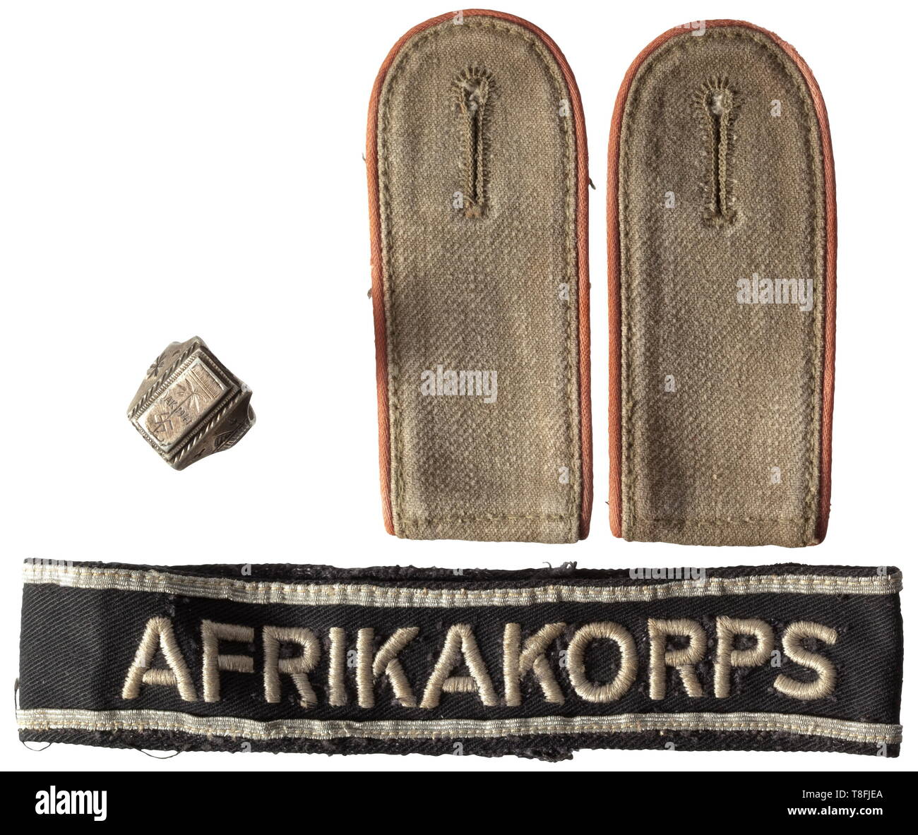 A cuff title, a pair of shoulder boards and a commemorative ring - Africa Corps The cuff title with black base cloth, stitched silver lace, machine-woven legend 'Afrikakorps', the ends stitched, total length circa 34 cm, width 35 mm. Also a pair of shoulder boards for enlisted men of beige linen cloth with field grey underlay, piped in pink for Panzer troops members, with loops, the slots separately stitched. Included is a silver ring with a stylised palm of the 'DAK 1941' and swastika, the sides with oriental décor, weight 11 g. Inner diameter 2, Additional-Rights-Clearance-Info-Not-Available Stock Photo