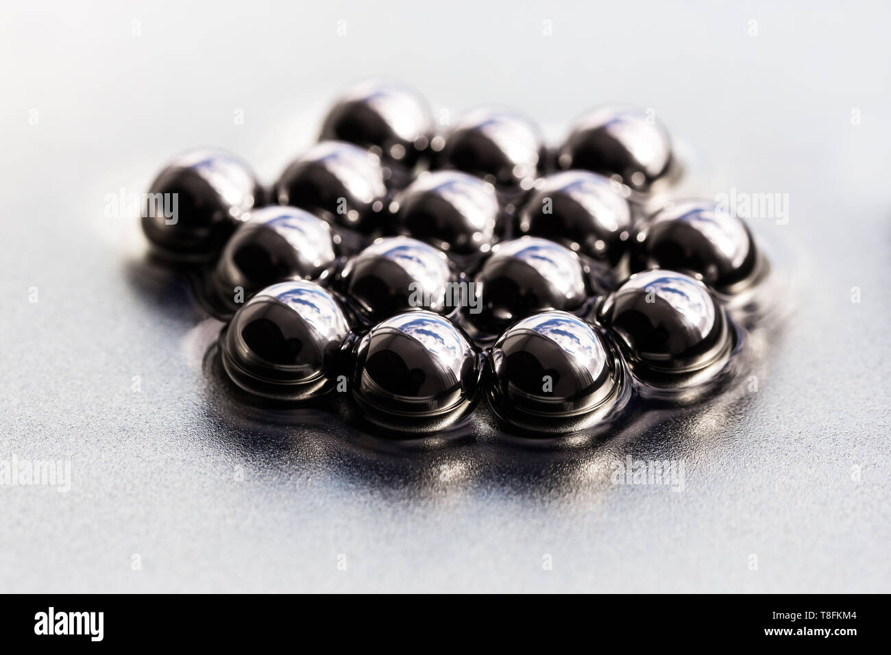 Steel balls with the sky reflected in them, in a liquid on a silver base Stock Photo