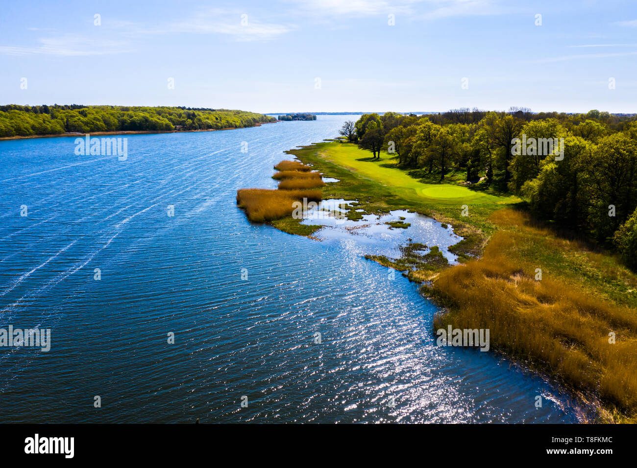 Golf green lovely situated by the sea with view of the surrounding springtime landscape. Sunlight reflected in the sea. The island Almo in Blekinge ar Stock Photo