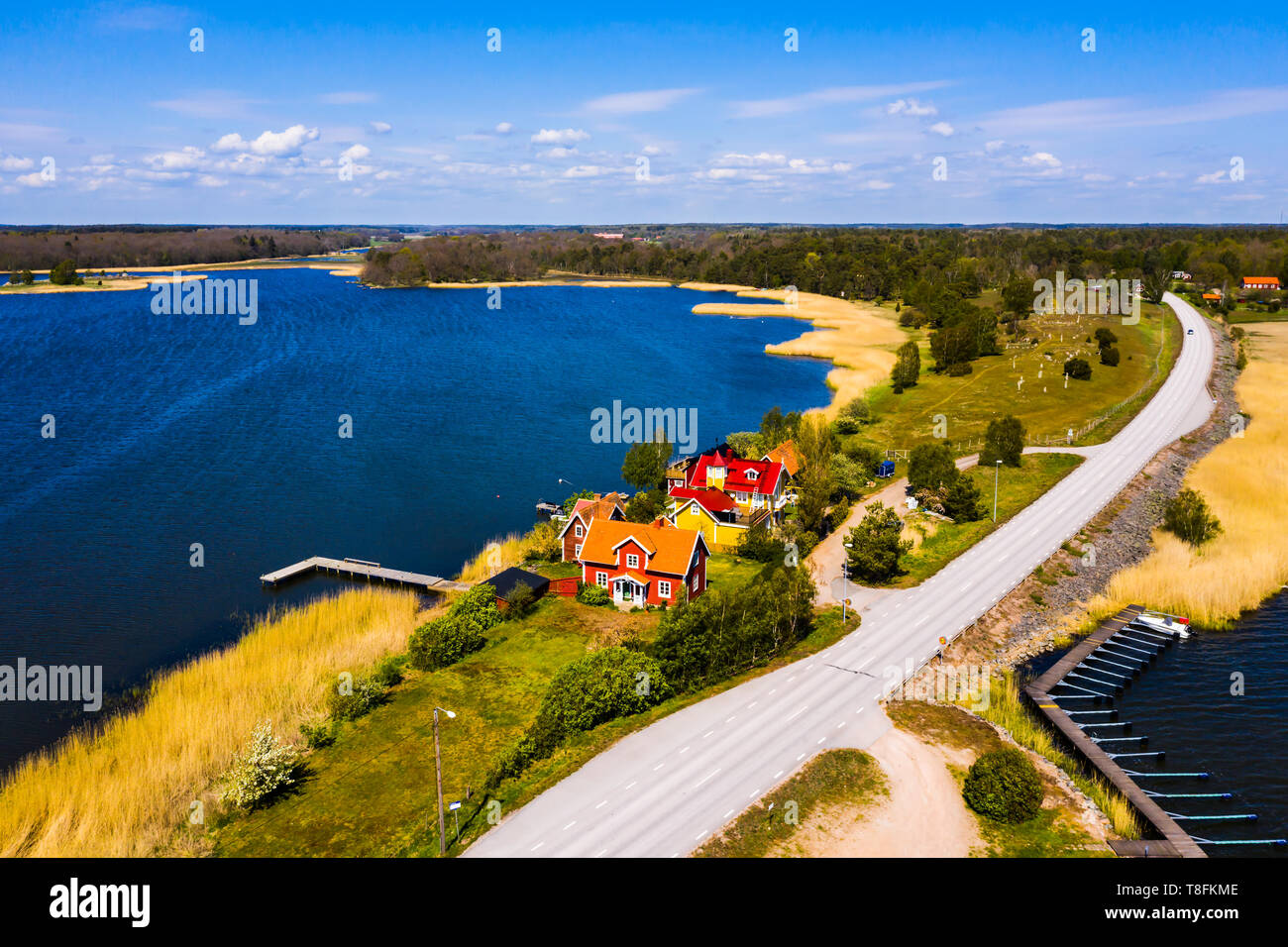Small seaside village in beautiful landscape on a sunny spring day. Situated on a narrow stretch of land beside a small road and surrounded by water.  Stock Photo