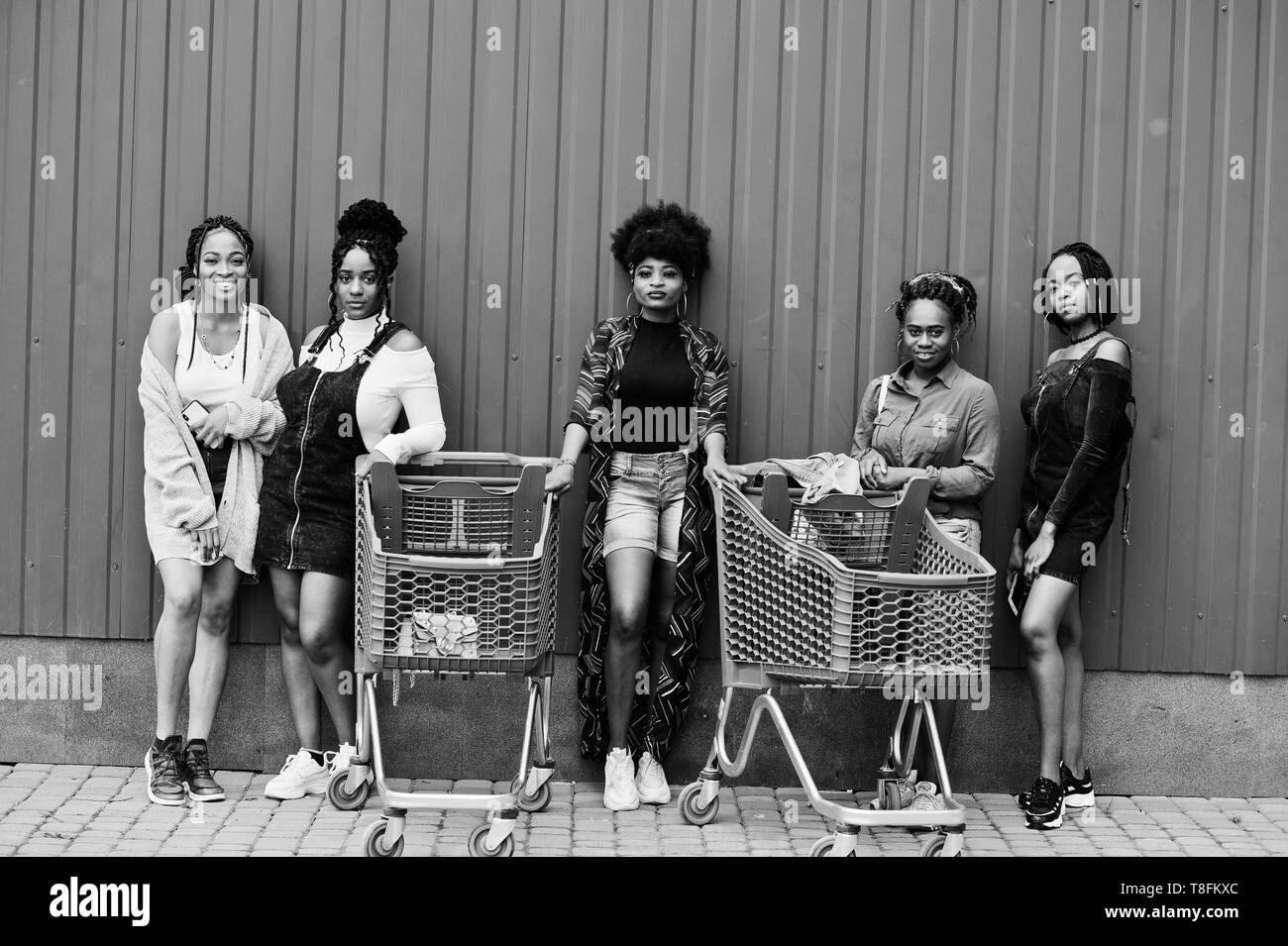 Group of five african american woman with shopping carts having fun together outdoor. Stock Photo