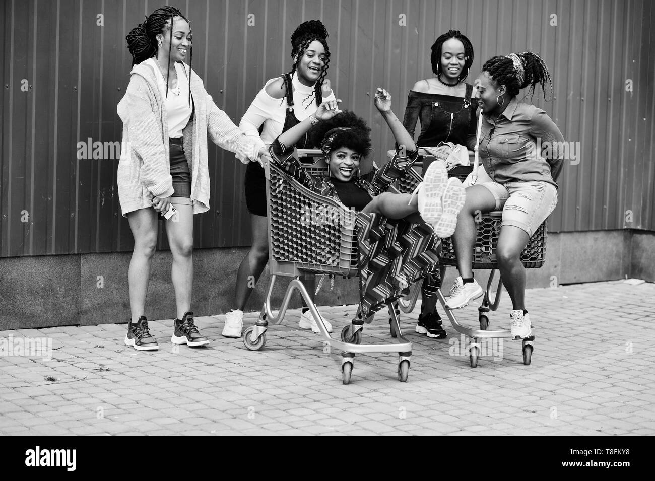 Group of five african american woman with shopping carts having fun together outdoor. Stock Photo