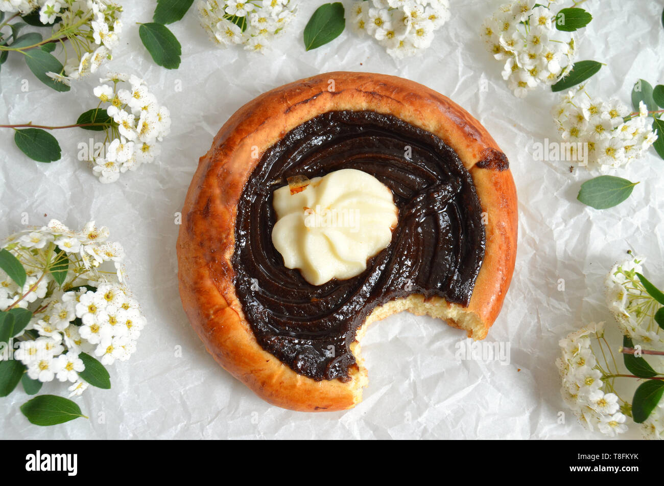Traditional czech baked pastry product - yeast dough kolache with dark plum preserve (povidla) and quark cheese (tvaroh). Kolach is lying on a paper s Stock Photo