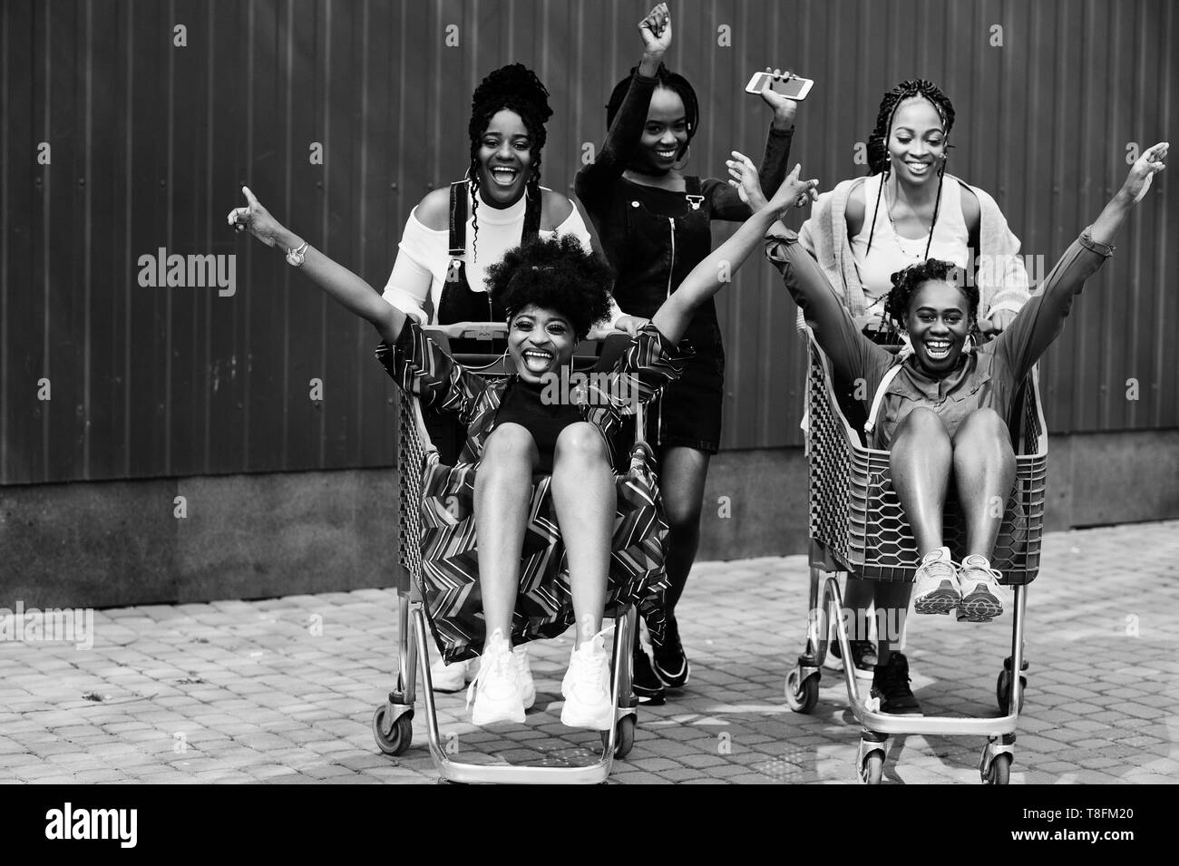 Group of five african american woman with shopping carts having fun together outdoor. Stock Photo