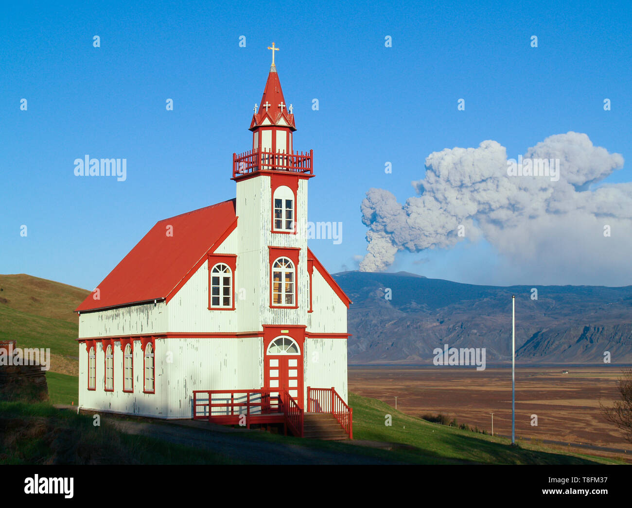 Volcanic eruption with church in foreground. Hlidarendi church and Eyjafjallajokull glacier and vocano. Stock Photo