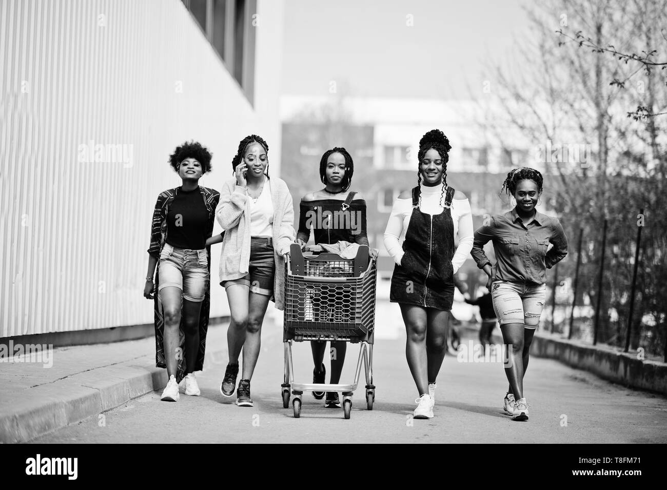 Group of five african american woman with shopping carts having fun together outdoor. Stock Photo