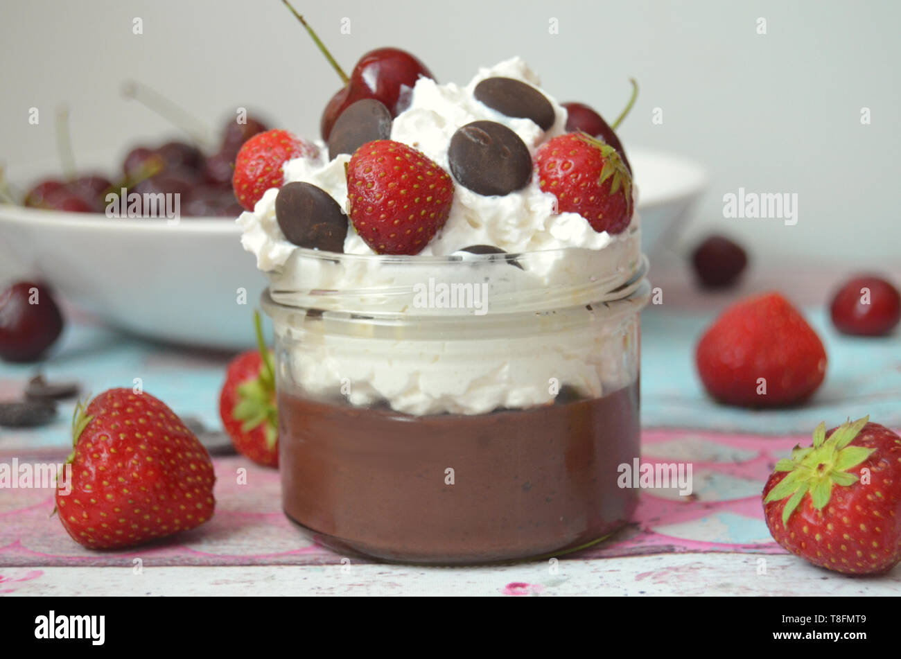Dairy free chocolate pudding in a jar with whipped coconut cream, topped with strawberies and dark chocolate chips Stock Photo