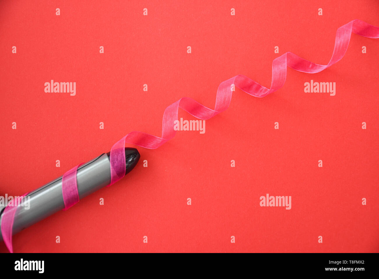 Curling iron isolated on red background. Stock Photo
