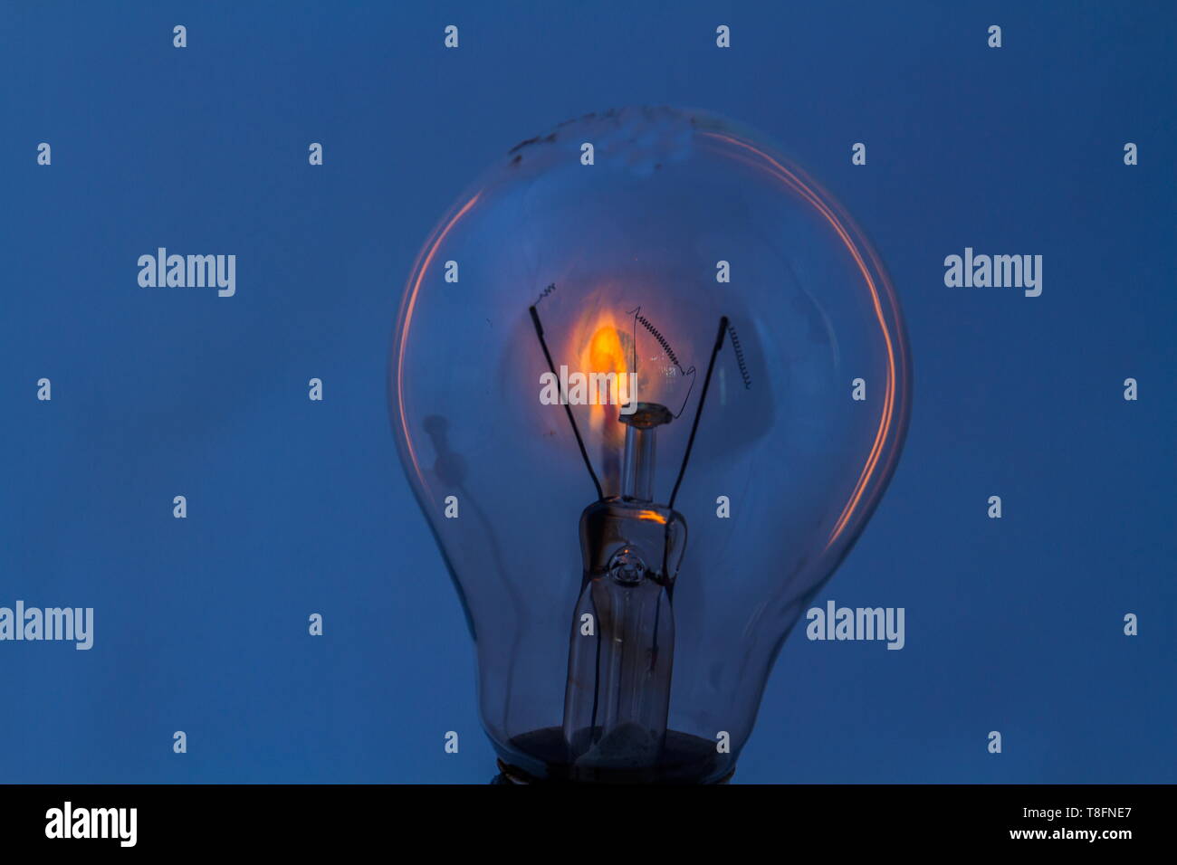 A dead electrical light bulb with a burning match behind it image in landscape format with copy