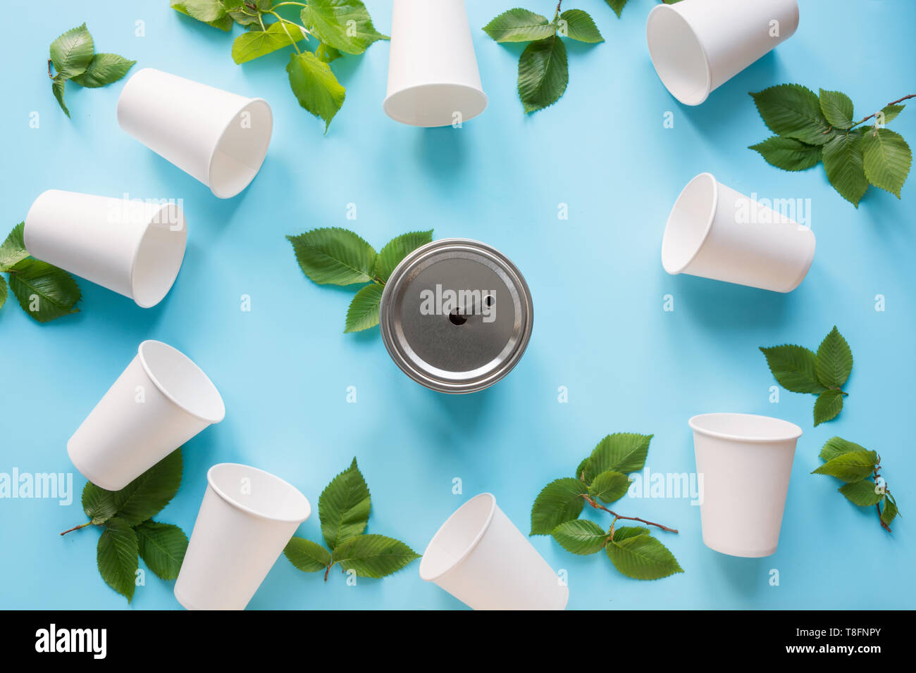 Border of white disposable cup and green leaves on blue background. Save the planet. Zero waste. Top view Stock Photo