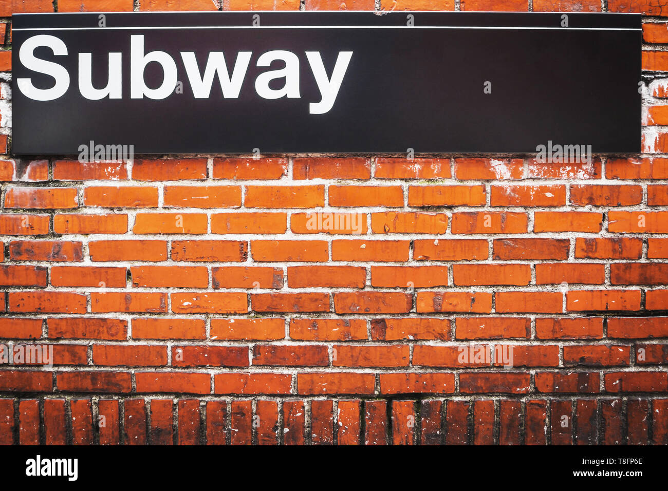 Subway sign of metro access on a red brick wall in New York City Stock Photo