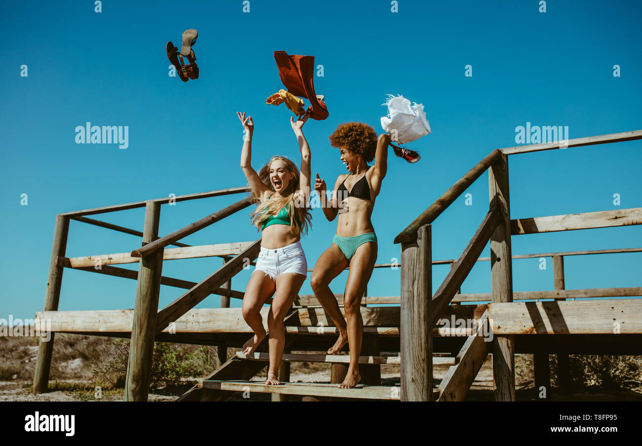 Woman friends taking off their clothes and throwing while running towards  the ocean. Excited women going for swimming in the sea on a summer day  Stock Photo - Alamy