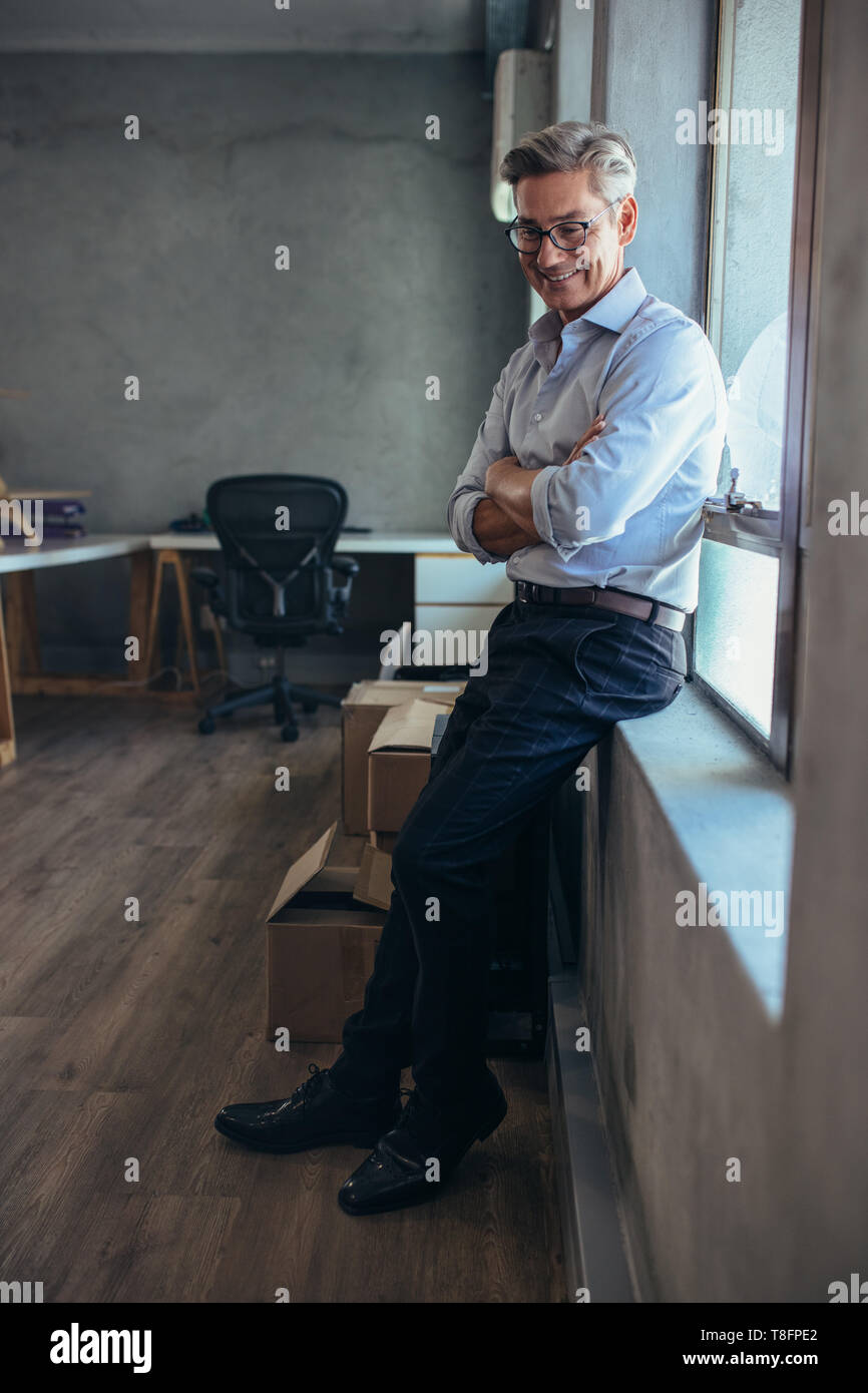 Happy mid adult man taking a break in office. Male business owner relaxing in office. Stock Photo