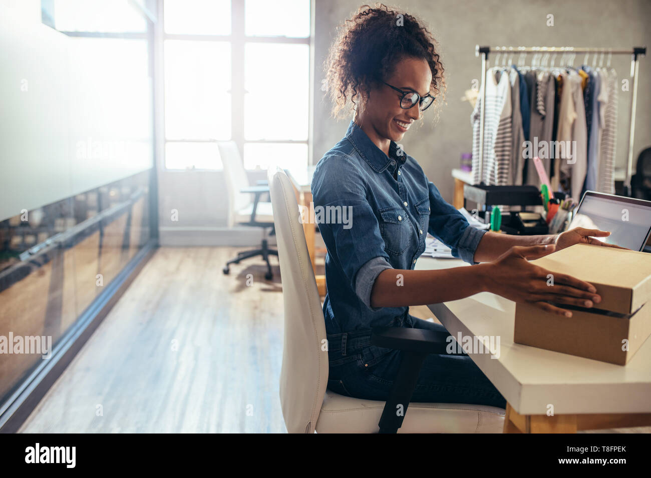 Woman packing the cardboard box on her desk. Businesswoman preparing product for deliver to customer. Stock Photo
