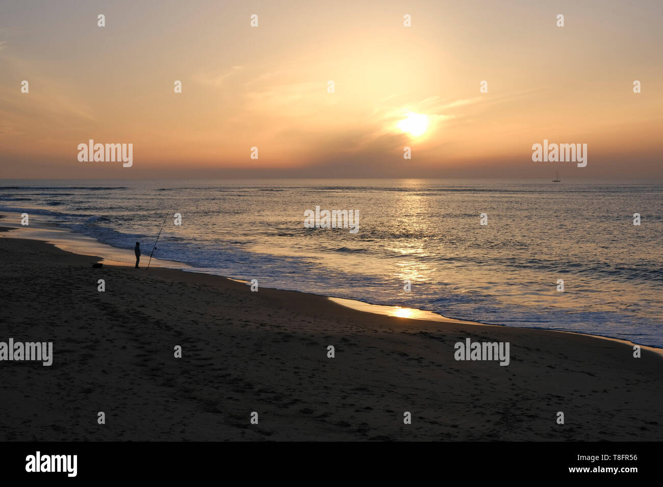 A lone fisherman at Playa Rota beach, as the sun sets, Rota, Andalucía, Spain. Stock Photo