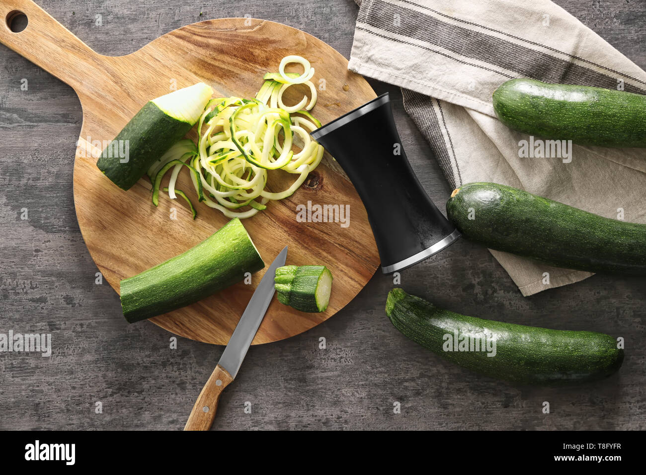 Fresh zucchini spaghetti with  spiral grater on wooden table Stock Photo