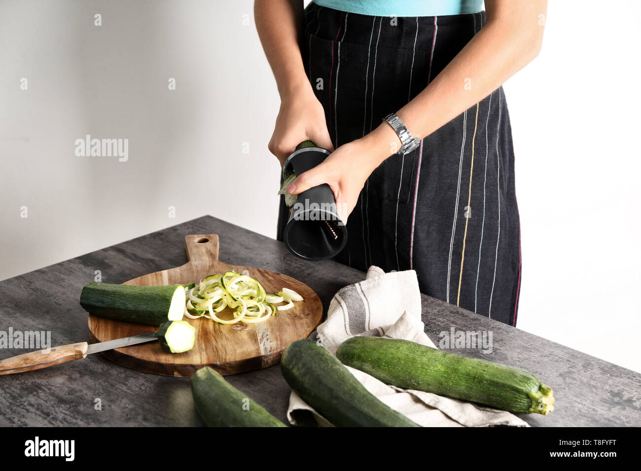 Woman making zucchini spaghetti on kitchen table Stock Photo