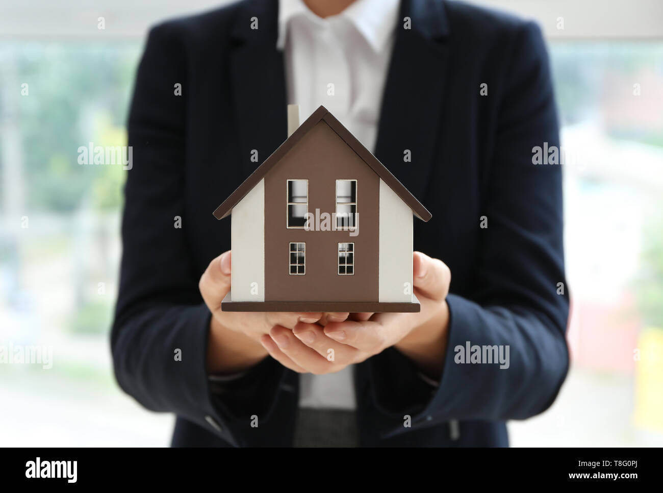 Real estate agent with house model indoors Stock Photo - Alamy