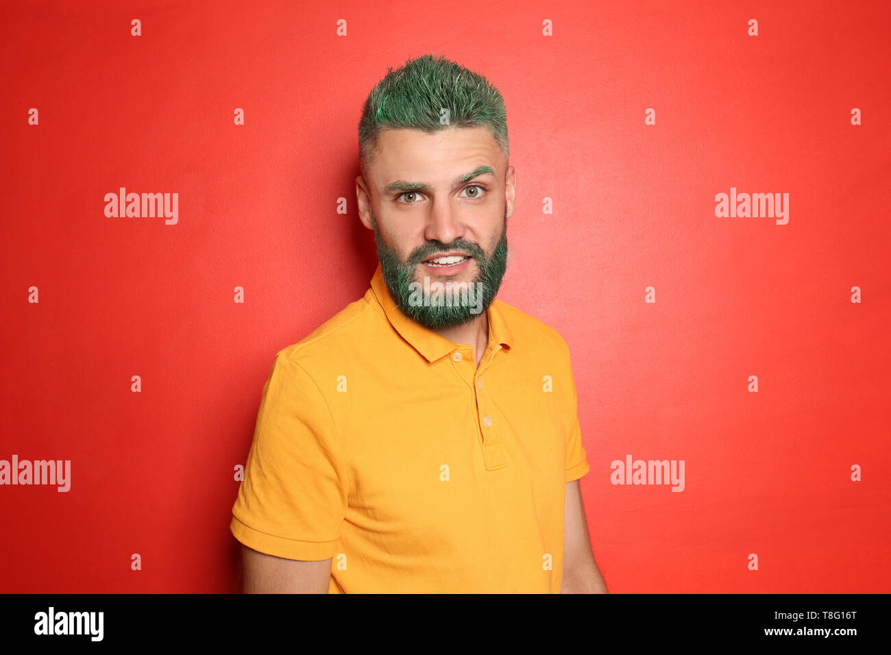 Portrait Of Handsome Man With Dyed Hair And Beard On Color