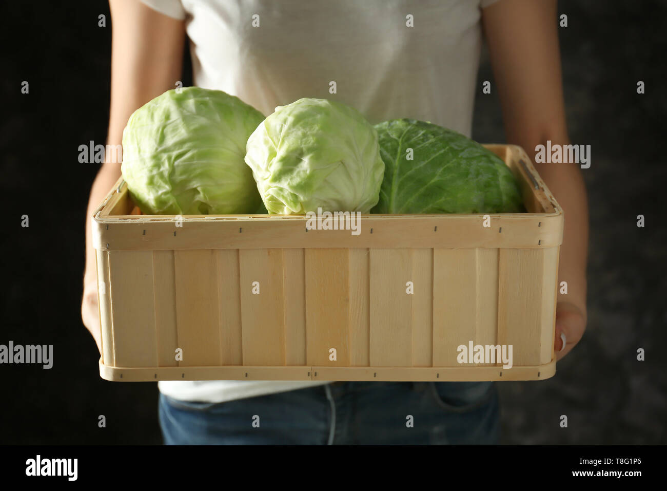 Woman holding wooden crate with cabbage on dark background Stock Photo -  Alamy, image size:1300x956