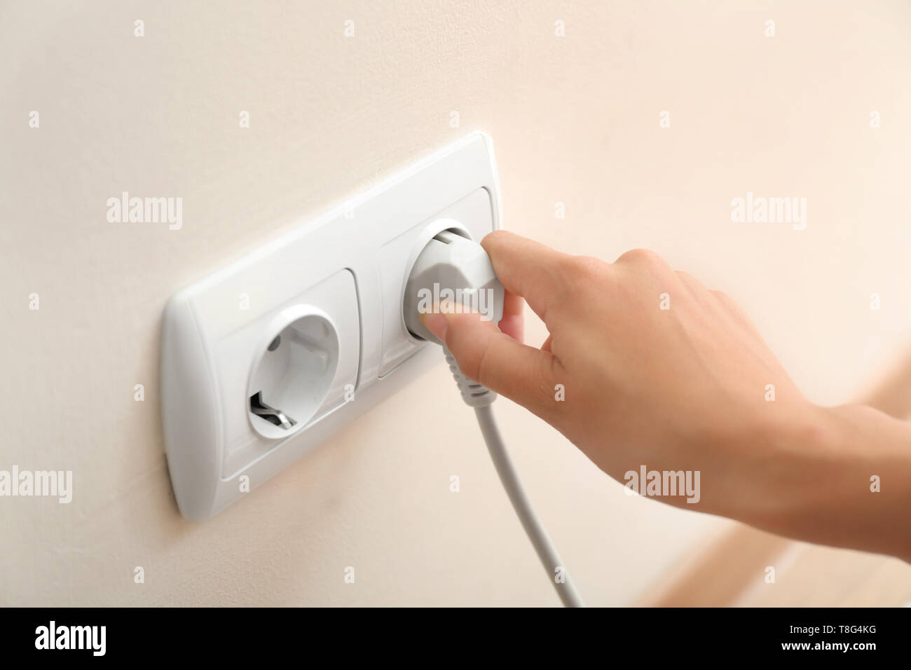 Woman getting out plug from socket. Electricity saving concept Stock