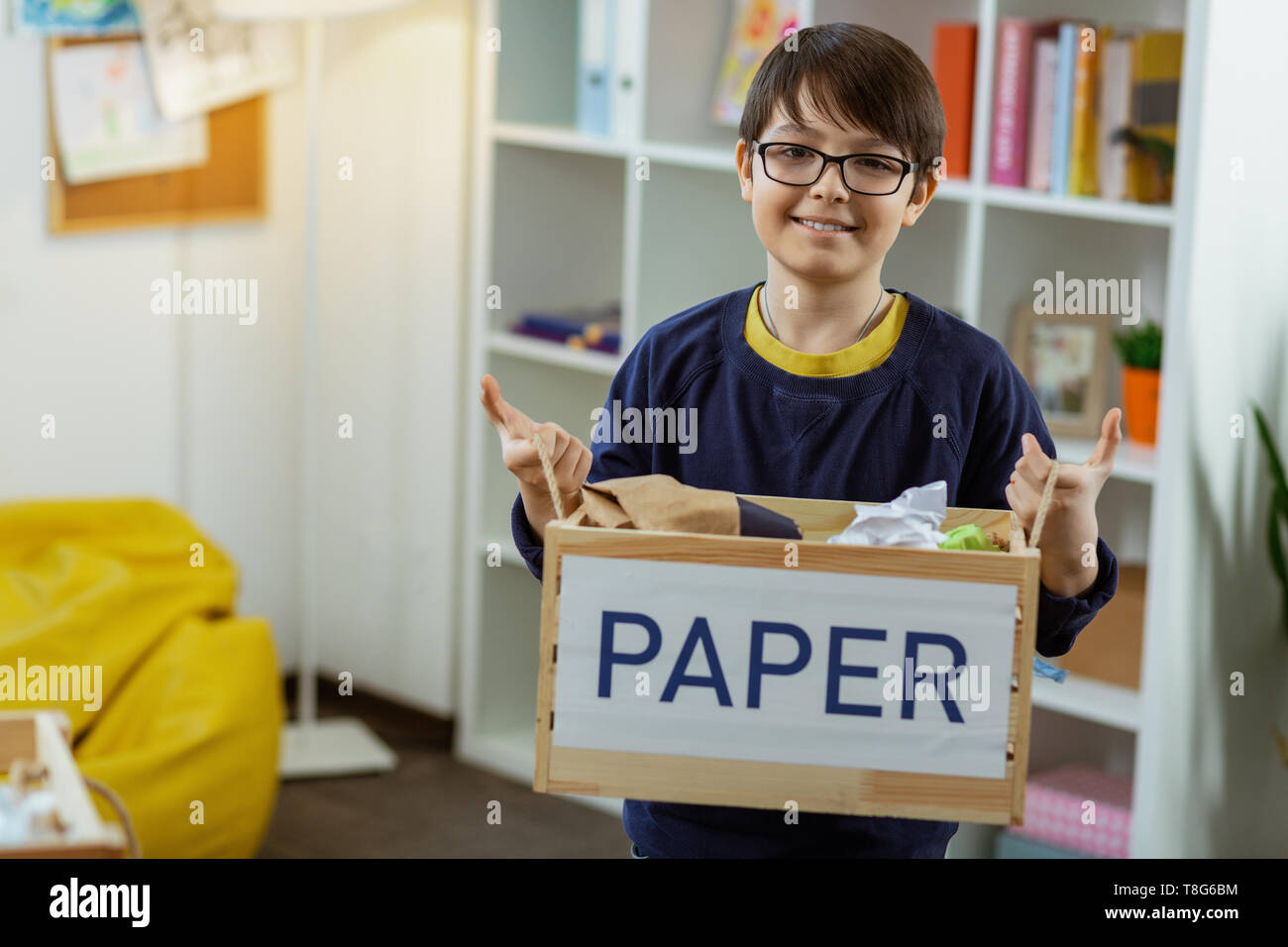 Pleasant dark haired boy carrying wooden box with paper inside Stock Pleasant dark haired boy carrying wooden box with paper inside Stock
