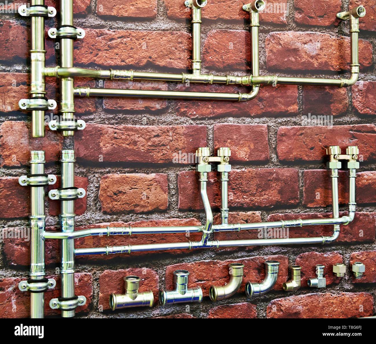 Metal plumbing pipes on a brick wall Stock Photo