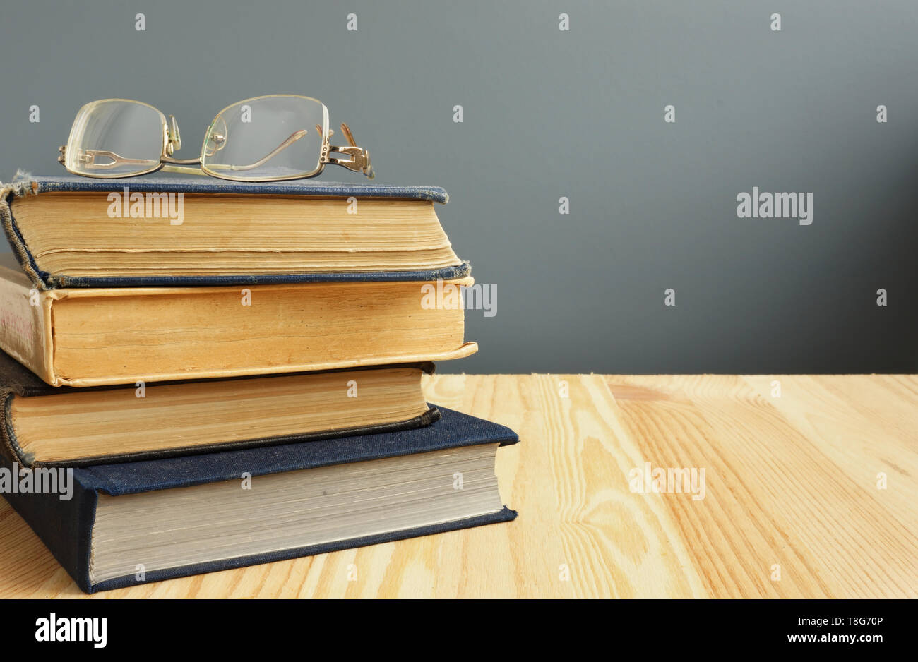 Retro books and old eyeglasses on wooden table. Stock Photo
