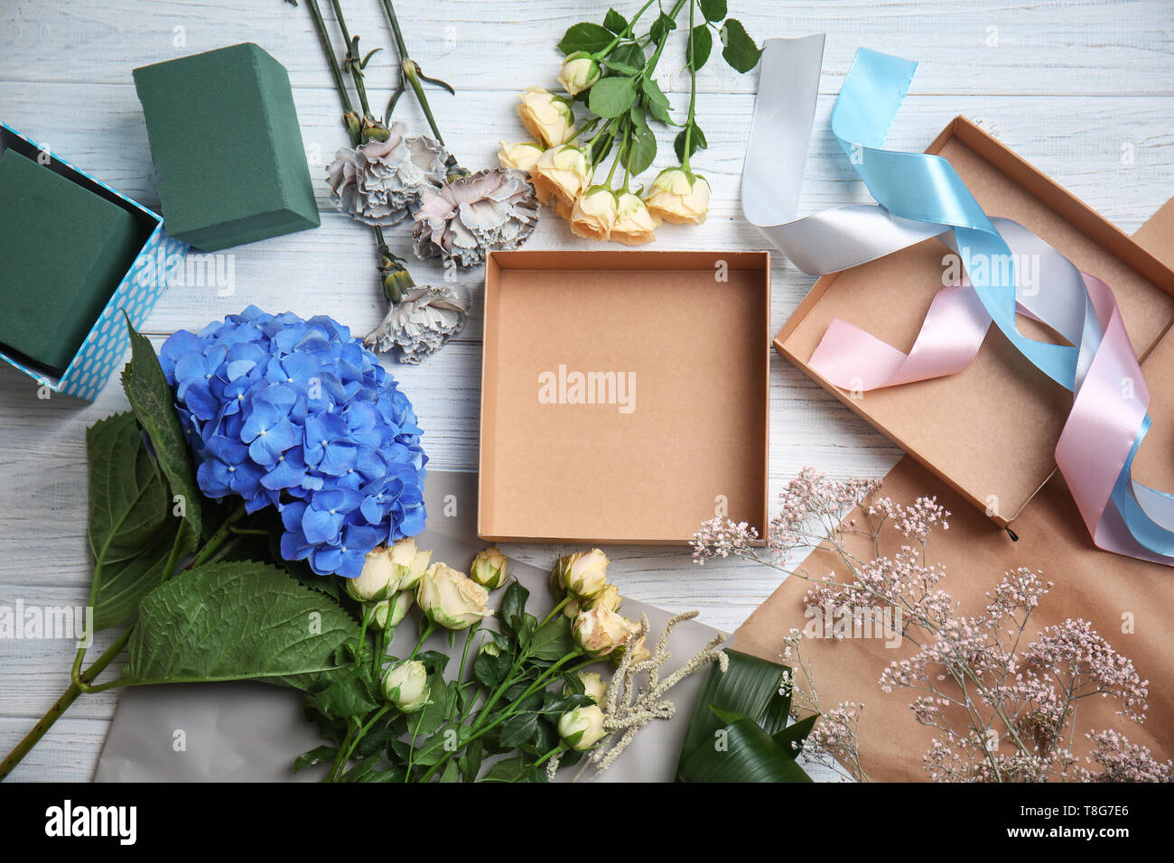 Florist's workplace with empty gift box and beautiful flowers on table Stock Photo